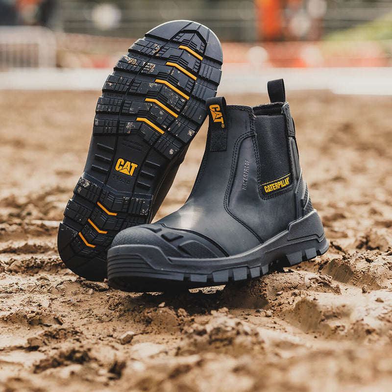 A pair of black Striver XL Dealer Boots on muddy ground