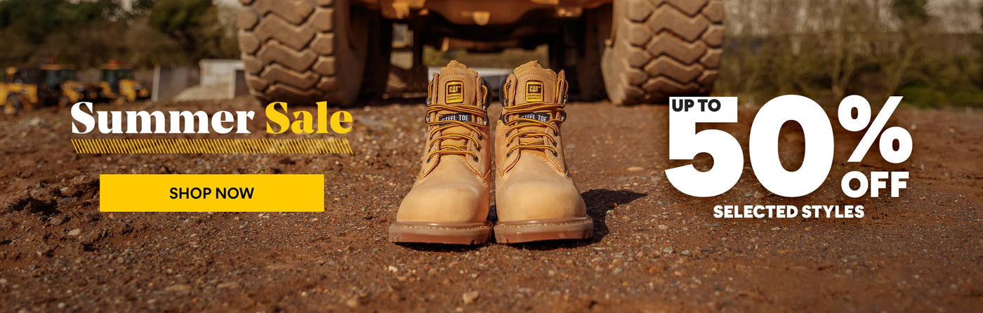 A pair of tan Caterpillar safety boots standing on dirt ground in front of construction equipment, with sale text overlays reading 'Summer Sale', 'SHOP NOW', and 'UP TO 50% OFF SELECTED STYLES'. Click to visit Caterpillar Sale collection.