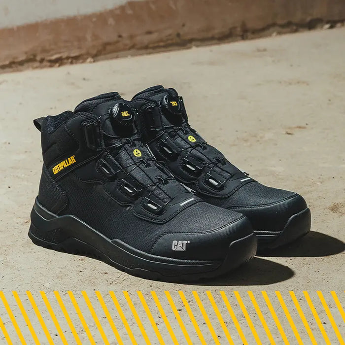 A pair of Caterpillar Inductor Tech Mid Boots in black on sand.
