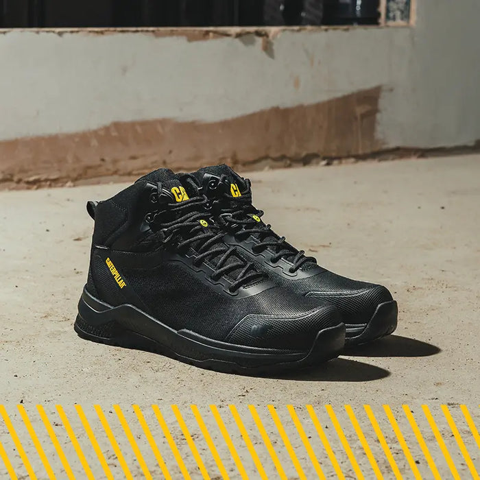 A pair of Caterpillar Mesh Mid Boots in black resting on sand.