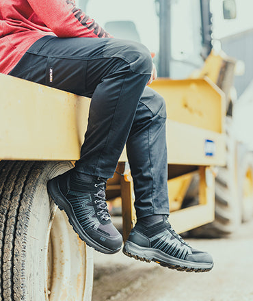 Man sat on a trailer, wearing a pair of black Caterpillar Dynamic Trousers and Caterpillar Charge Hiker boots